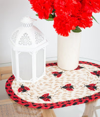 Ladybug placemat or trivet with red and black ladybugs design, red and black border and tan braided jute. 